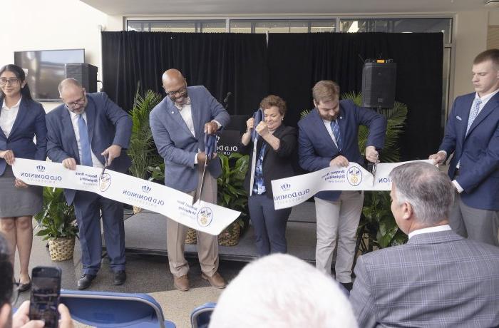 Five people at a ribbon cutting event. 